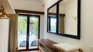 A hotel room with a sliding glass door leading to a balcony, a large mirror, a wooden bench, and a woven basket with a white towel. - Los Suspiros Hotel Boutique & Spa (Comala)