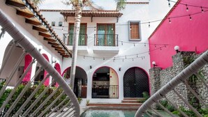 A courtyard with a pool, palm trees, and a building with arched doorways. - Los Suspiros Hotel Boutique & Spa (Comala)