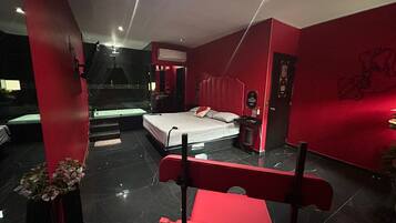 Quarto de hotel moderno com uma cama grande, uma mesa de escritório e uma área de estar.