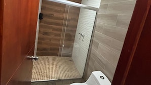 A bathroom with a shower, toilet, and wooden cabinets. - Hotel-Motel Deluxe (Tecuala)