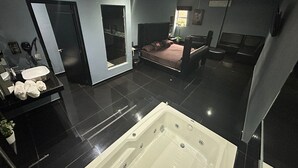 A modern bathroom with a large bathtub, a vanity with a mirror, and a shower area. - Hotel-Motel Deluxe (Tecuala)