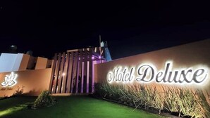The exterior of the Motel Deluxe with a prominent illuminated sign, a modern design with vertical slats, and a well-maintained lawn. - Hotel-Motel Deluxe (Tecuala)