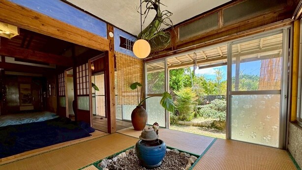 A traditional Japanese room with tatami flooring, a shoji screen, and a view of a garden.