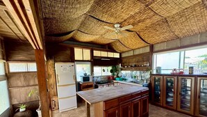 A kitchen with a wooden island, a ceiling fan, and a view of the outside.