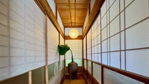 A traditional hallway with wooden beams, tatami flooring, and shoji screens.