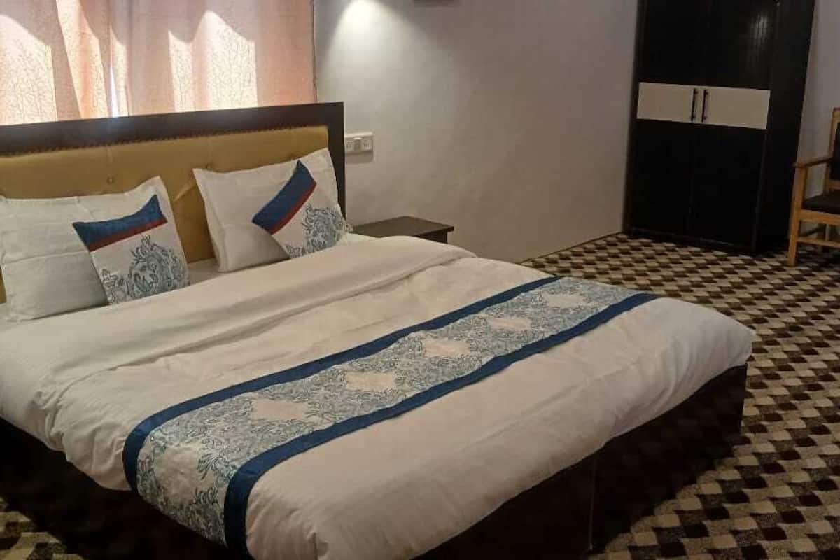 A neatly made bed with a patterned bedspread, a wooden headboard, and a checkered floor.