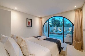 A bedroom with a large bed, a view of a pool and outdoor seating, and a framed picture on the wall. - 3BR Rooftop Summary: (Kabupaten Badung)