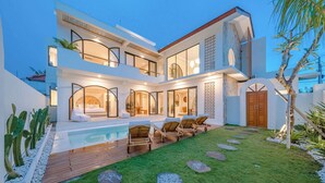 A modern two-story house with a swimming pool, outdoor seating, and a well-maintained garden. - 3BR Rooftop Summary: (Kabupaten Badung)