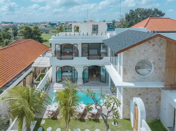 A modern two-story house with a swimming pool, glass-enclosed balconies, and a stone facade. - 3BR Rooftop Summary: (Kabupaten Badung)
