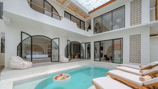 A modern indoor pool area with lounge chairs and a floating bar. - 3BR Rooftop Summary: (Kabupaten Badung)
