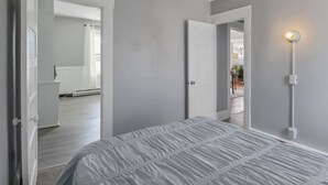Quarto com cama, porta e luminária.
