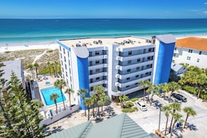 A multi-story hotel with a pool, beach view, and palm trees. - 🌞Chambre 103- Beachfront, Pool, Hot Tub, Walk to John's Pass! (Madeira Beach)