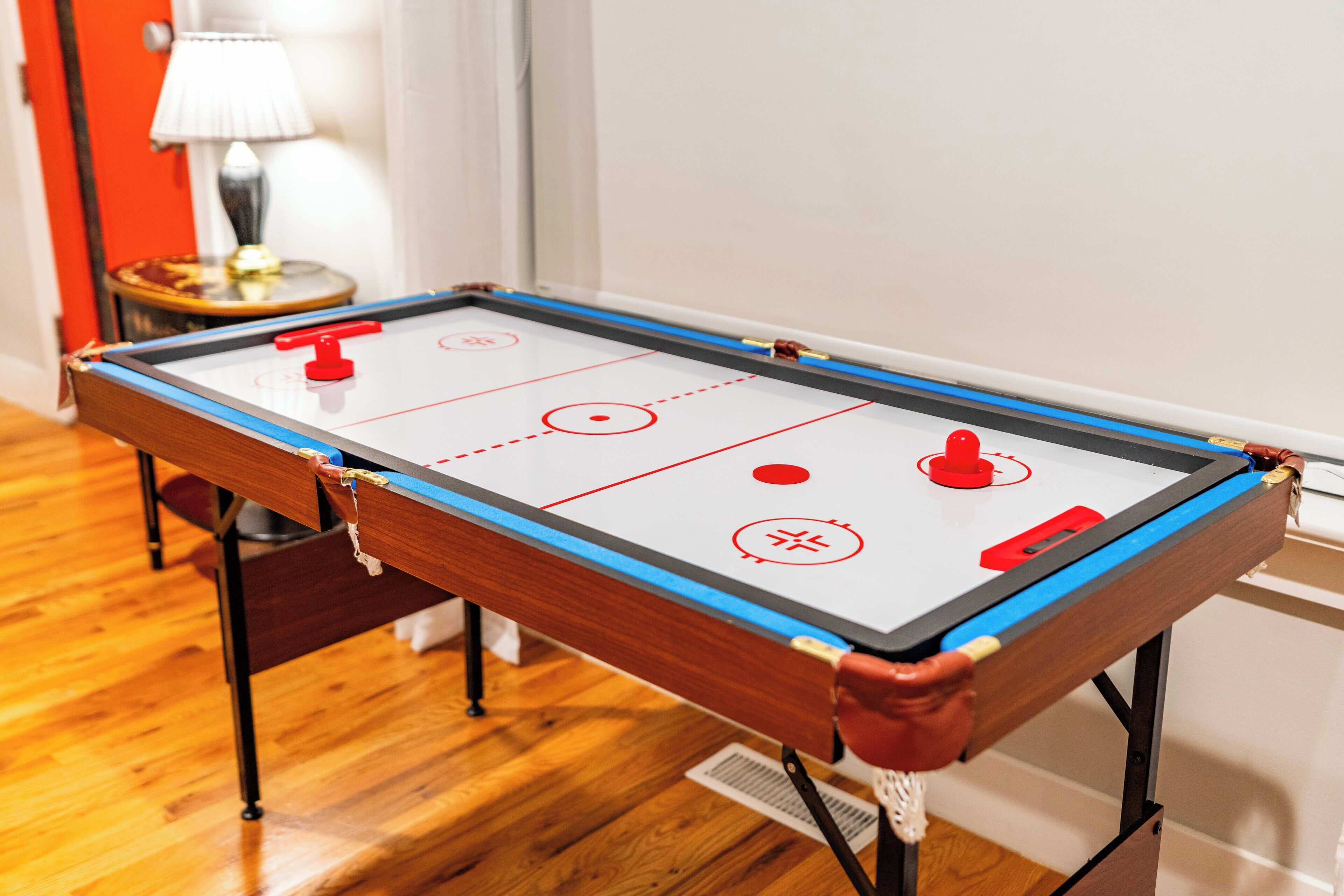 A pool table with a red puck, a lamp, and a red door in the background.