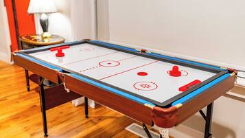 A pool table with a red puck, a lamp, and a red door in the background.