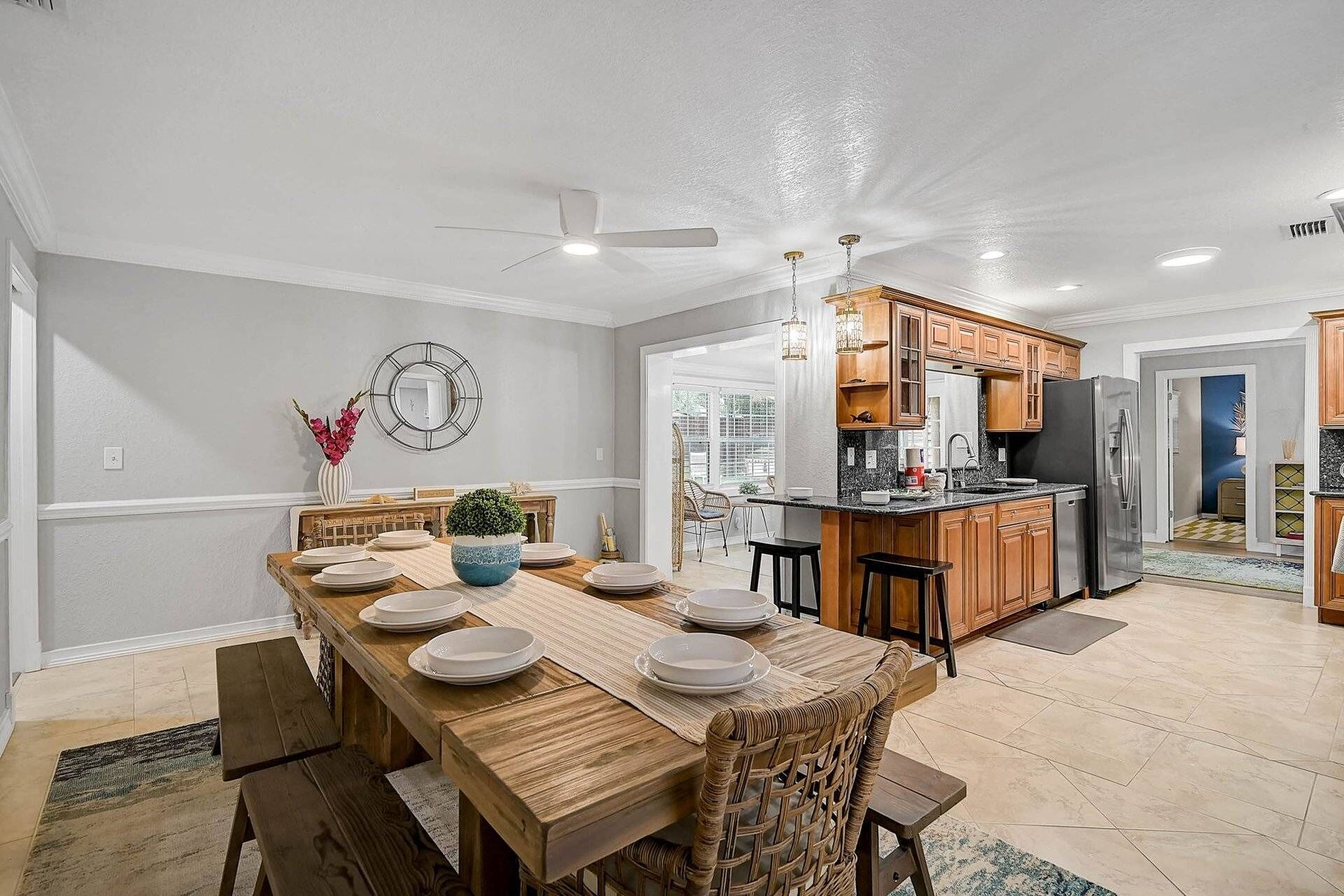 A modern kitchen with wooden cabinets, a stainless steel refrigerator, and a dining area with a wooden table and chairs.