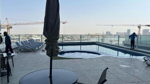Terraza en la azotea con piscina, sillones de descanso y una mesa.