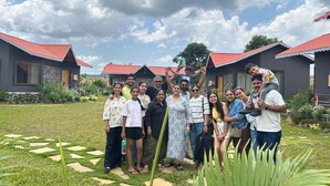 A group of people posing in a garden with a house in the background.
