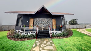 A modern house with a tiled roof, a stone facade, and a small porch with potted plants.