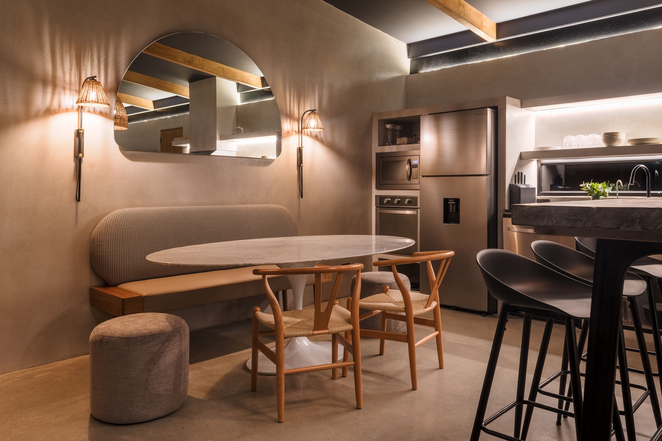 Une cuisine moderne avec une table de salle à manger ronde, des chaises en bois, un banc et un four encastré.