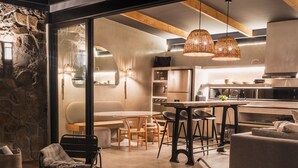 A modern kitchen with a dining area, featuring a wooden floor, a bar area, and a seating arrangement.