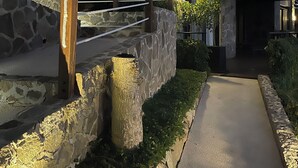 A modern house with a stone facade, a wooden deck, and a concrete pathway.
