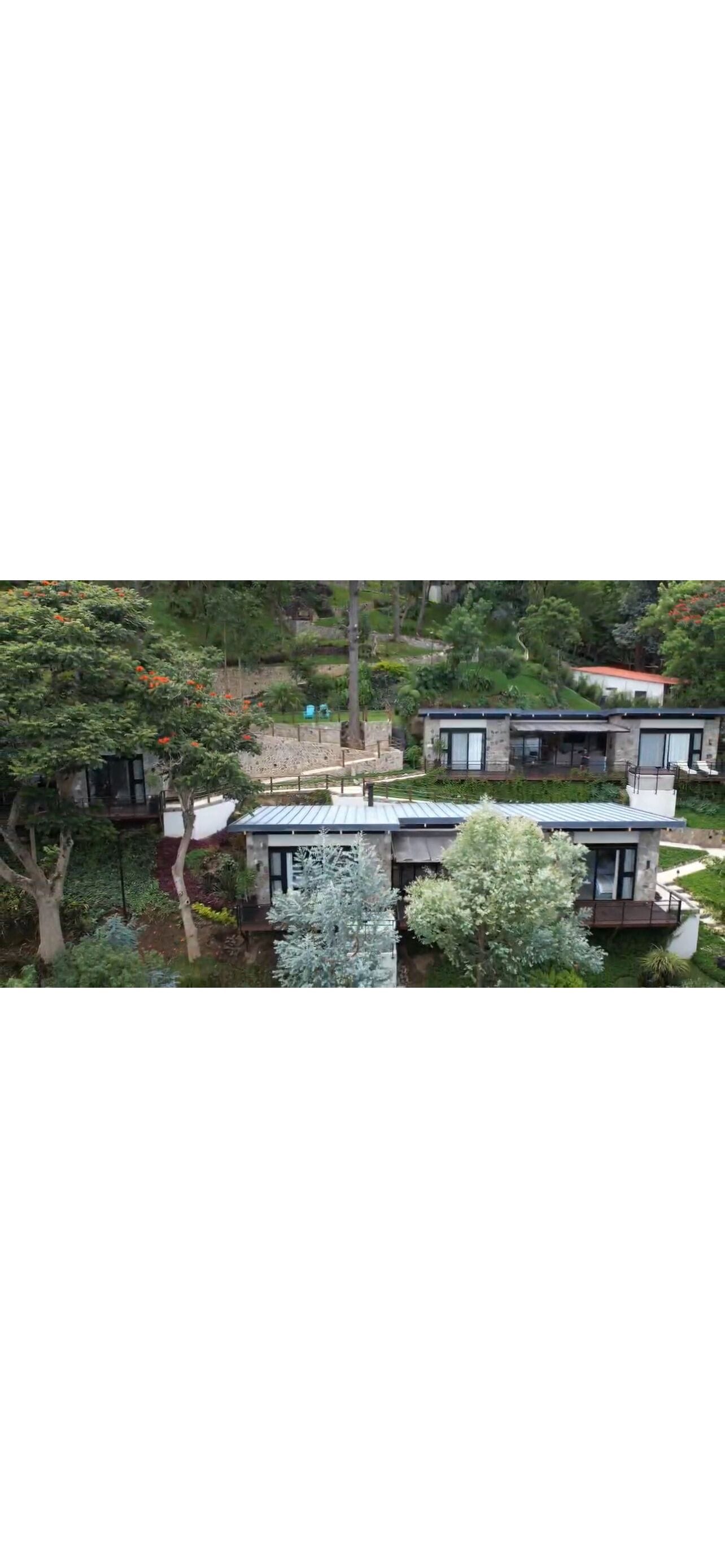 Une maison moderne à deux étages, dotée d’un toit plat, de grandes fenêtres et d’un jardin bien entretenu.