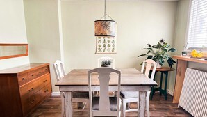 Un coin repas avec une table et des chaises en bois, un luminaire suspendu et une plante en pot.