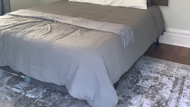 Makuuhuone, jossa on sänky, sängynpääty, taulu ja matto.
