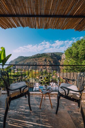 A terrace with two chairs, a table, and a view of a mountainous landscape.