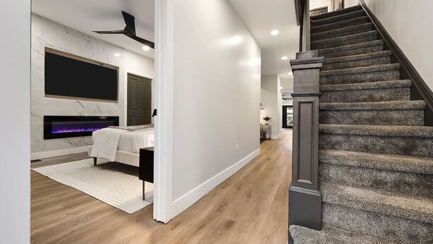 A modern interior with a staircase, a fireplace, and a hallway leading to another room.