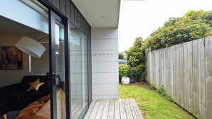 A modern living room with a glass door leading to a wooden deck. - Canvas of Comfort — A Modern Townhouse of Four Suites (Hamilton)