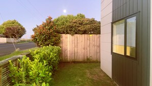 A fenced backyard with a wooden fence, a grassy lawn, and a building with large windows. - Canvas of Comfort — A Modern Townhouse of Four Suites (Hamilton)