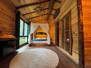A wooden cabin bedroom with a canopy bed, a round rug, and a large window.