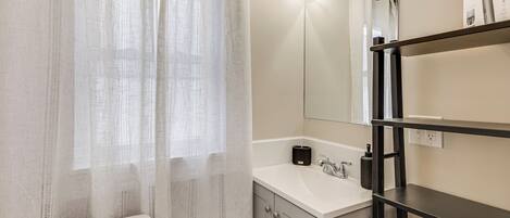 Une salle de bain équipée de toilettes, d’un lavabo, d’un miroir et d’une étagère.