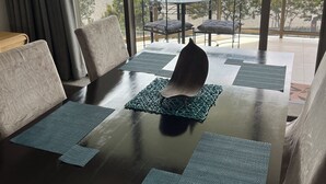 Een eetgedeelte met een tafel gedekt voor vier personen, een uitzicht op een stadshemelbeeld door grote ramen en een balkon met zitplaatsen buiten.