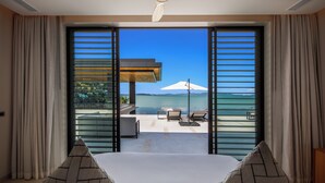 Une chambre dotée d’une grande porte-fenêtre coulissante donnant sur un balcon avec vue sur la mer.