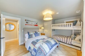 Ein Schlafzimmer mit einem Etagenbett, einem großen Bett mit Steppdecke, einem runden Spiegel und einem Schild mit der Aufschrift 'No Wake Zone'.