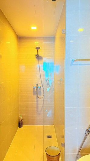Une salle de bain moderne dotée d’une douche à parois de verre, d’un pommeau de douche à main et d’un flexible de douche.