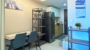 A modern kitchen with a dining area, featuring a refrigerator, cabinets, and a dining table with chairs. - Your Perfect Home Base — Comfort and Convenience! (Taguig)