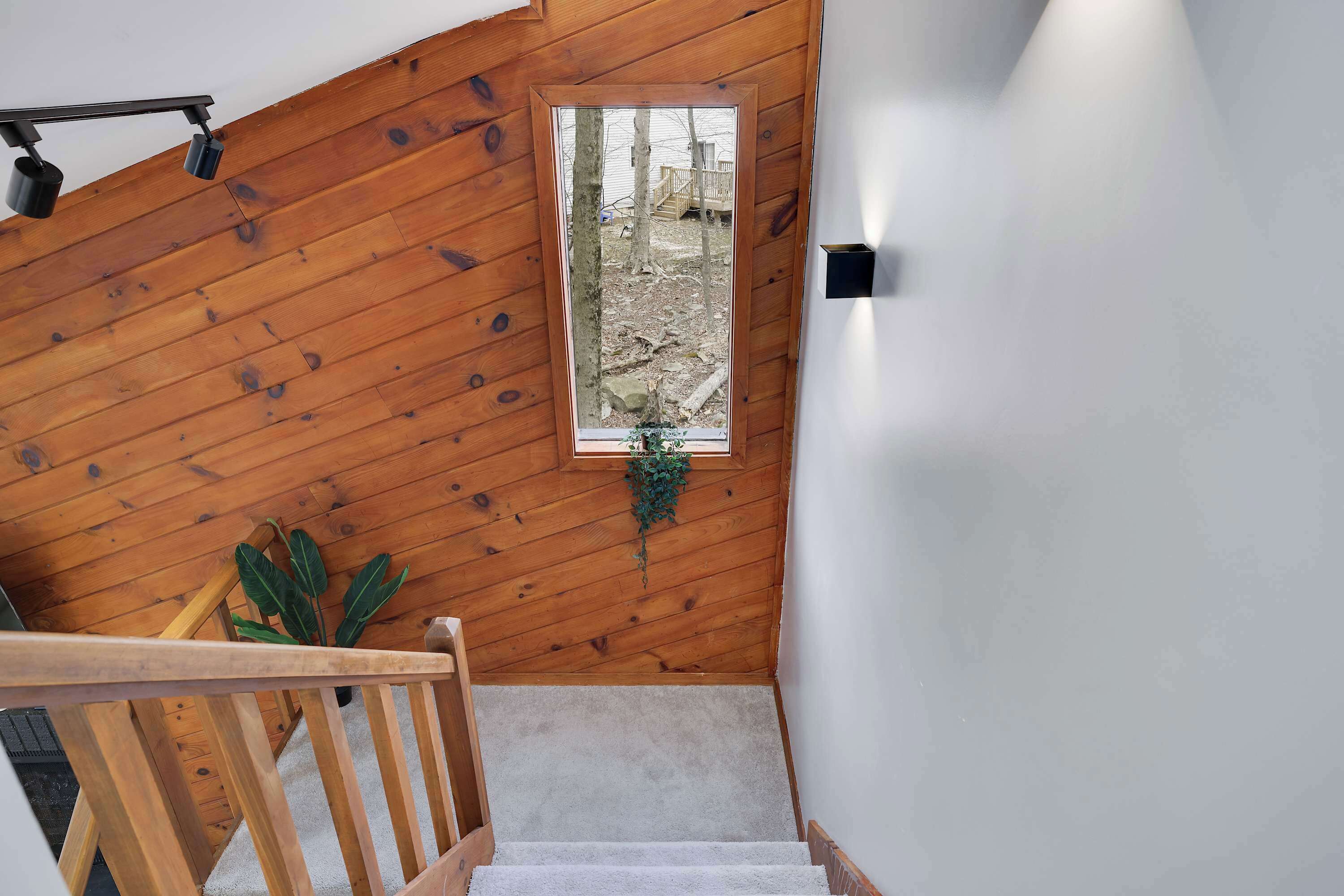 Una escalera de madera con vista a un patio trasero a través de un ventanal.