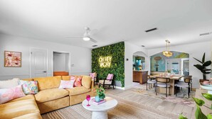 Ein modernes Wohnzimmer mit einer Couch, einem Couchtisch und einer grünen Wand mit einem Neonzeichen.