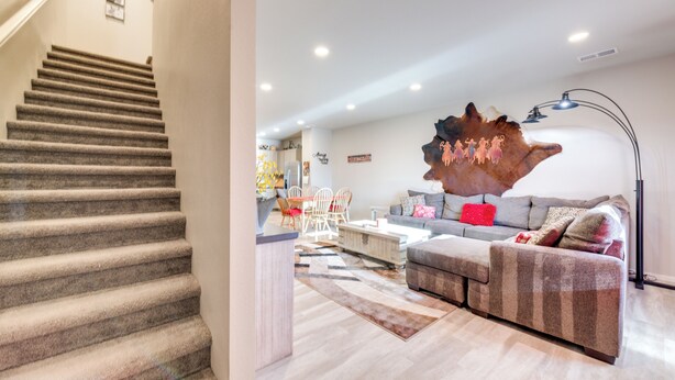 A staircase leading to a living area with a sofa and a large decorative piece on the wall.