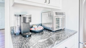 Una cocina con cafetera, microondas y un tazón de bocadillos sobre la encimera.