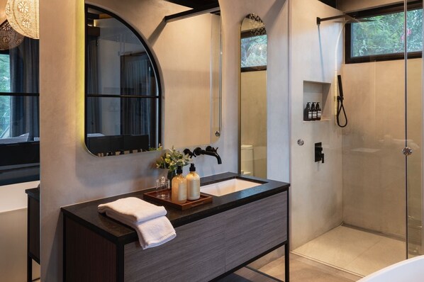 Un baño moderno con tocador, un espejo grande, ducha y ventana.
