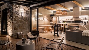 A modern kitchen with a stone accent wall, wooden beams, and a dining area with a round table and chairs.