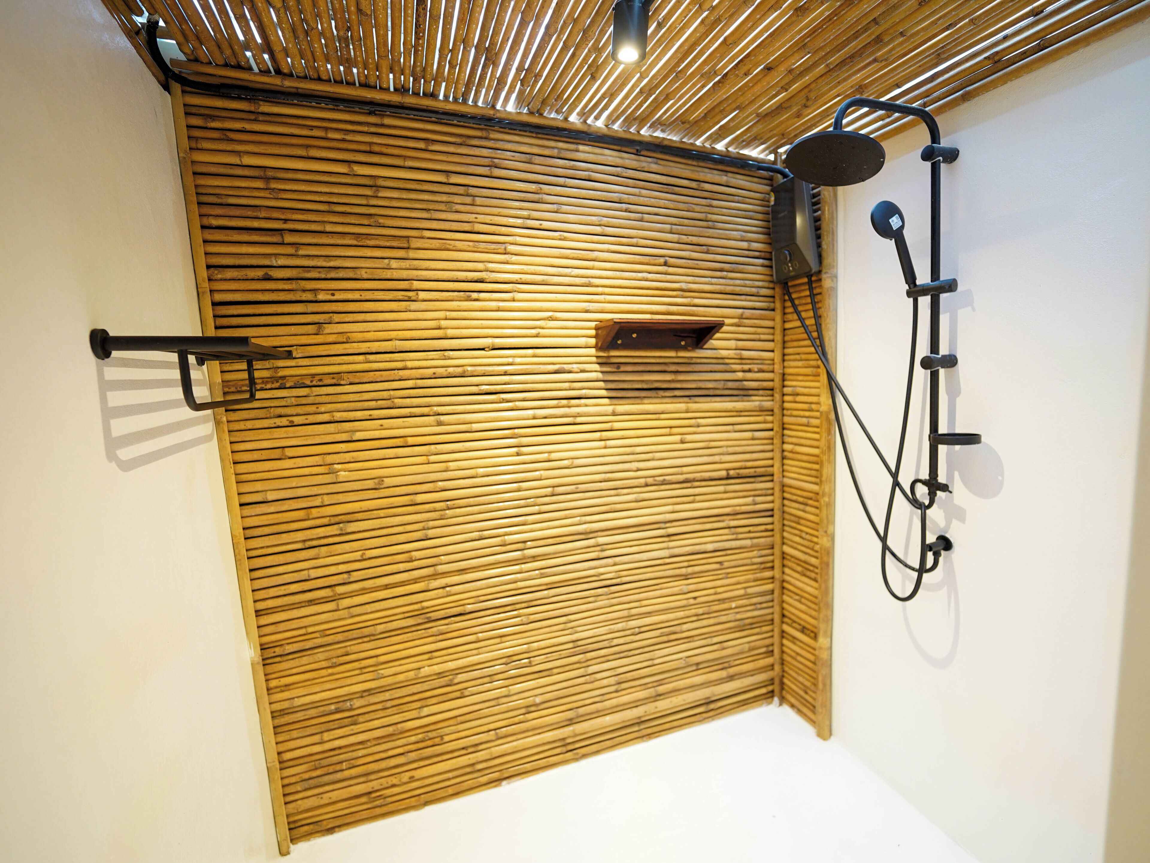 Una habitación con un panel de pared de bambú, un perchero y un cabezal de ducha.