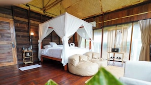 A room with a four-poster bed, a sofa, a coffee table, and a large window with curtains. - RoomQuest THEVA Resort koh Samui  (Koh Samui)