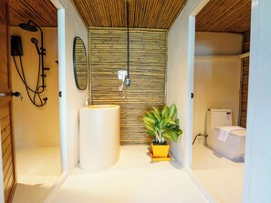 A bathroom with a bamboo wall, a sink, a mirror, a shower, and a toilet. - RoomQuest THEVA Resort koh Samui (Koh Samui)
