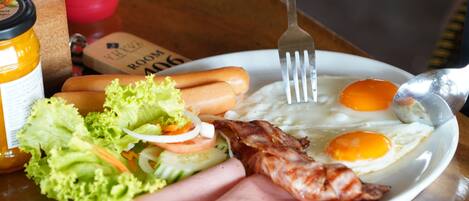 A breakfast plate with eggs, bacon, ham, and a side salad.