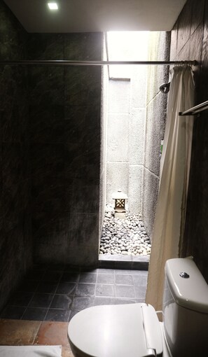 A bathroom with a toilet, shower, and a small window. - ME Villas Echo Beach (Canggu)